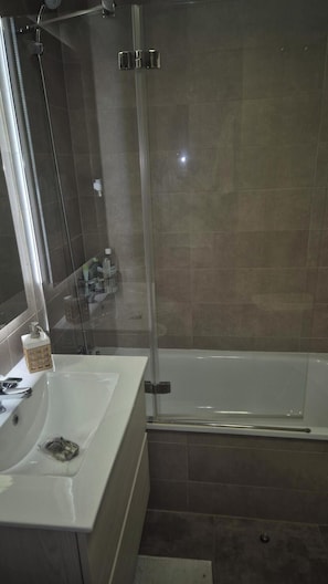 Ein Badezimmer mit einer Duschkabine, einem weißen Waschbecken und einer Badewanne.