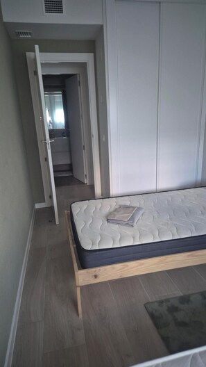 Ein Schlafzimmer mit einem Bett, einem Kleiderschrank und einer Tür zu einem anderen Raum.