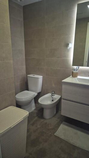 Ein Badezimmer mit Toilette, Bidet und Waschbecken mit Spiegel.