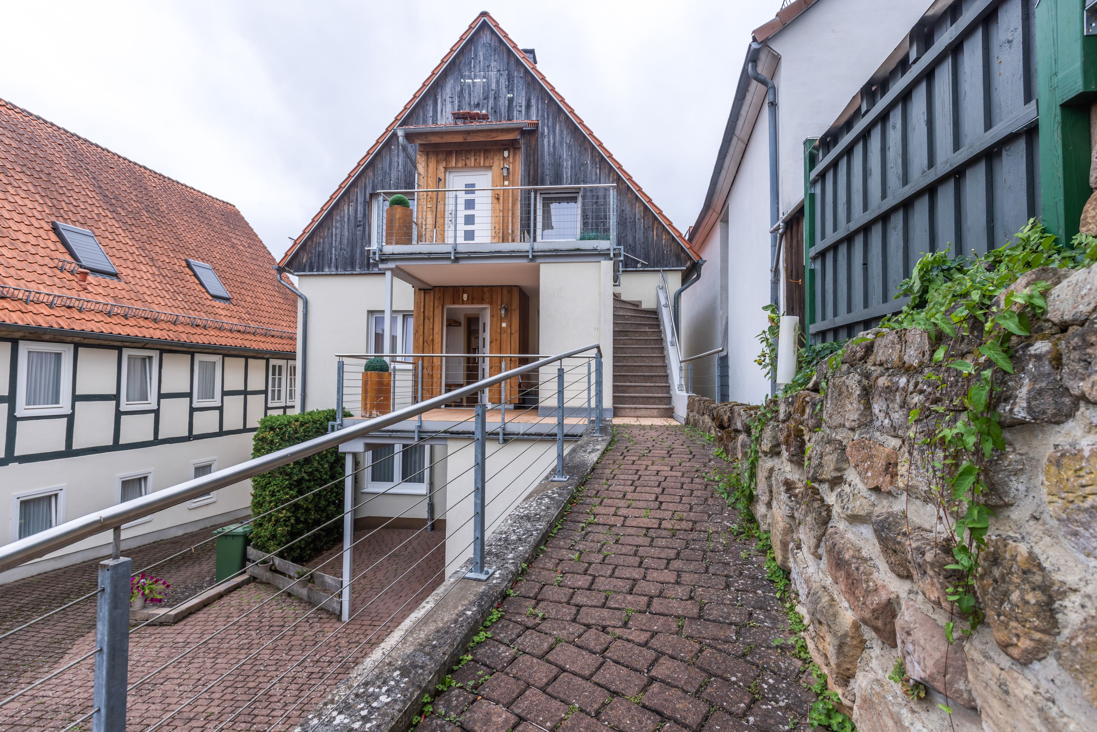 Een gebouw met twee verdiepingen, met een houten gevel, een balkon en een trap naar de bovenverdieping.