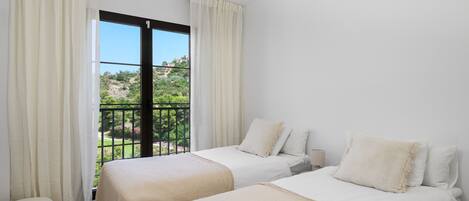 Une chambre d’hôtel avec deux lits, un balcon et une vue sur une colline.