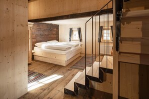 Un interior de madera con una cama, una escalera y una ventana.