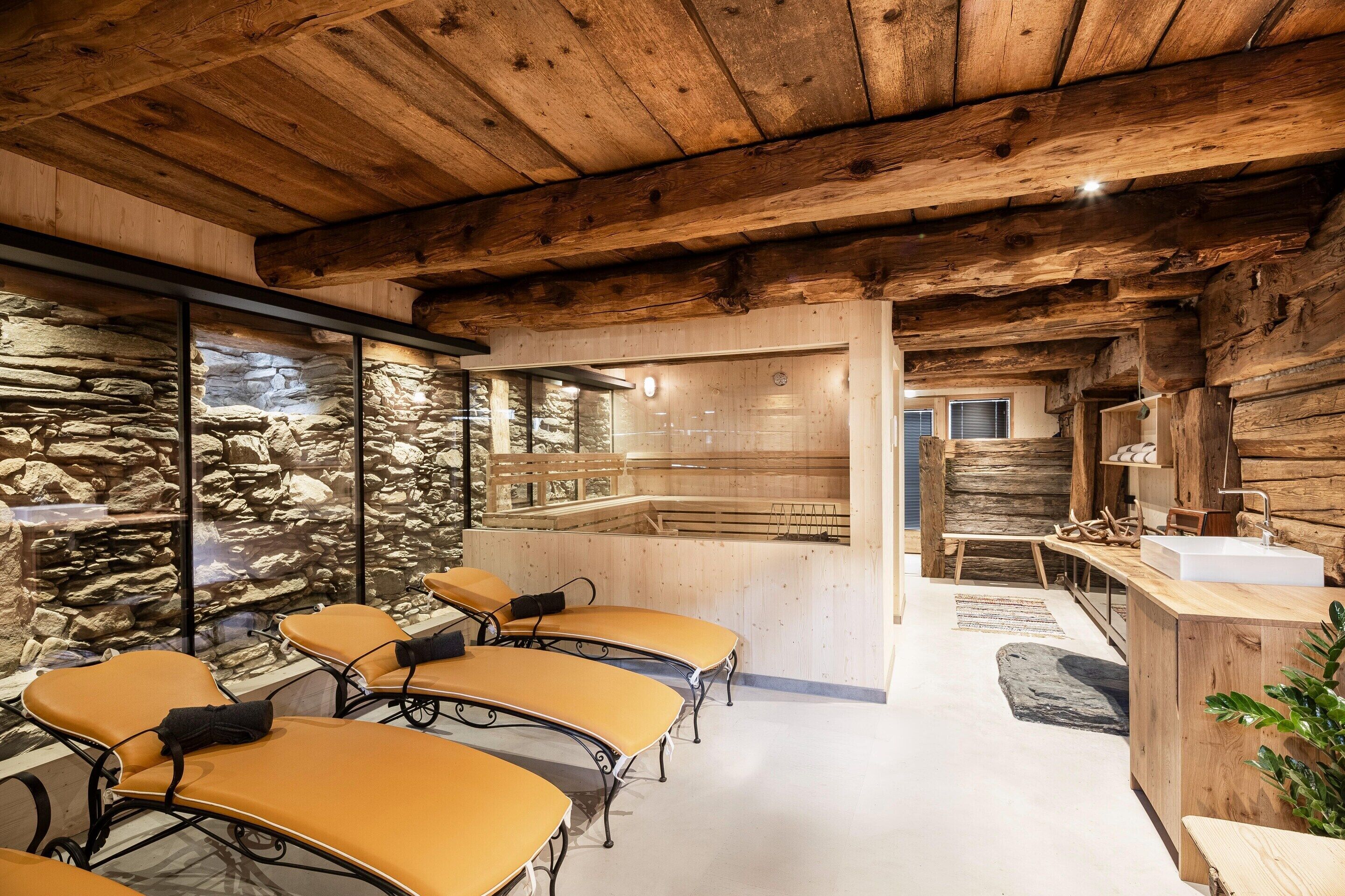A rustic interior with stone walls, wooden beams, and a stone sauna.