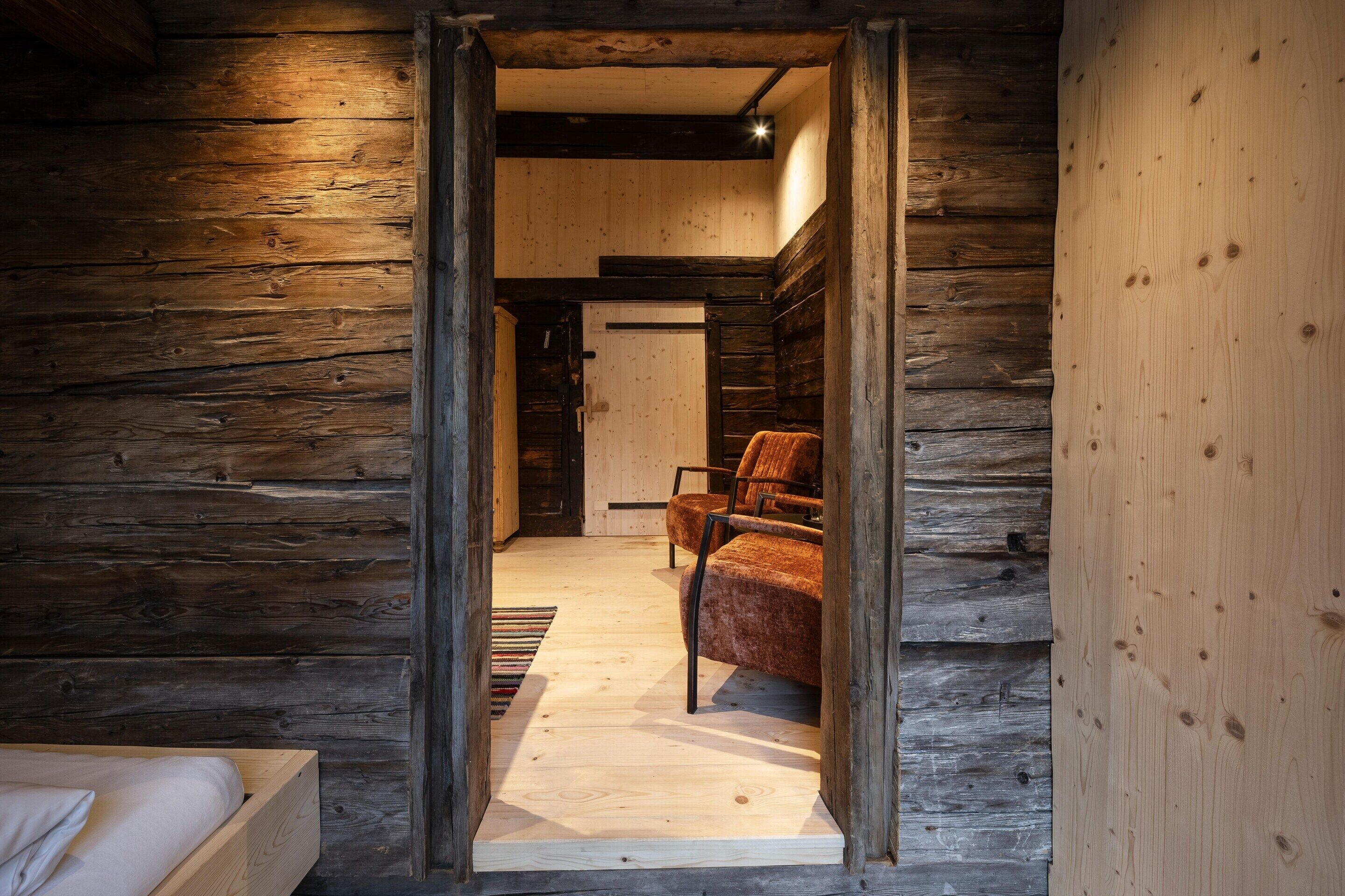Interior de madeira com uma cama, uma cadeira e piso de madeira.