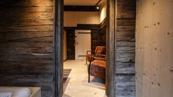 Interior de madeira com uma cama, uma cadeira e piso de madeira.