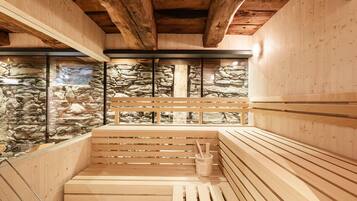 Una sauna con bancos de madera, paredes de piedra y techo de madera.
