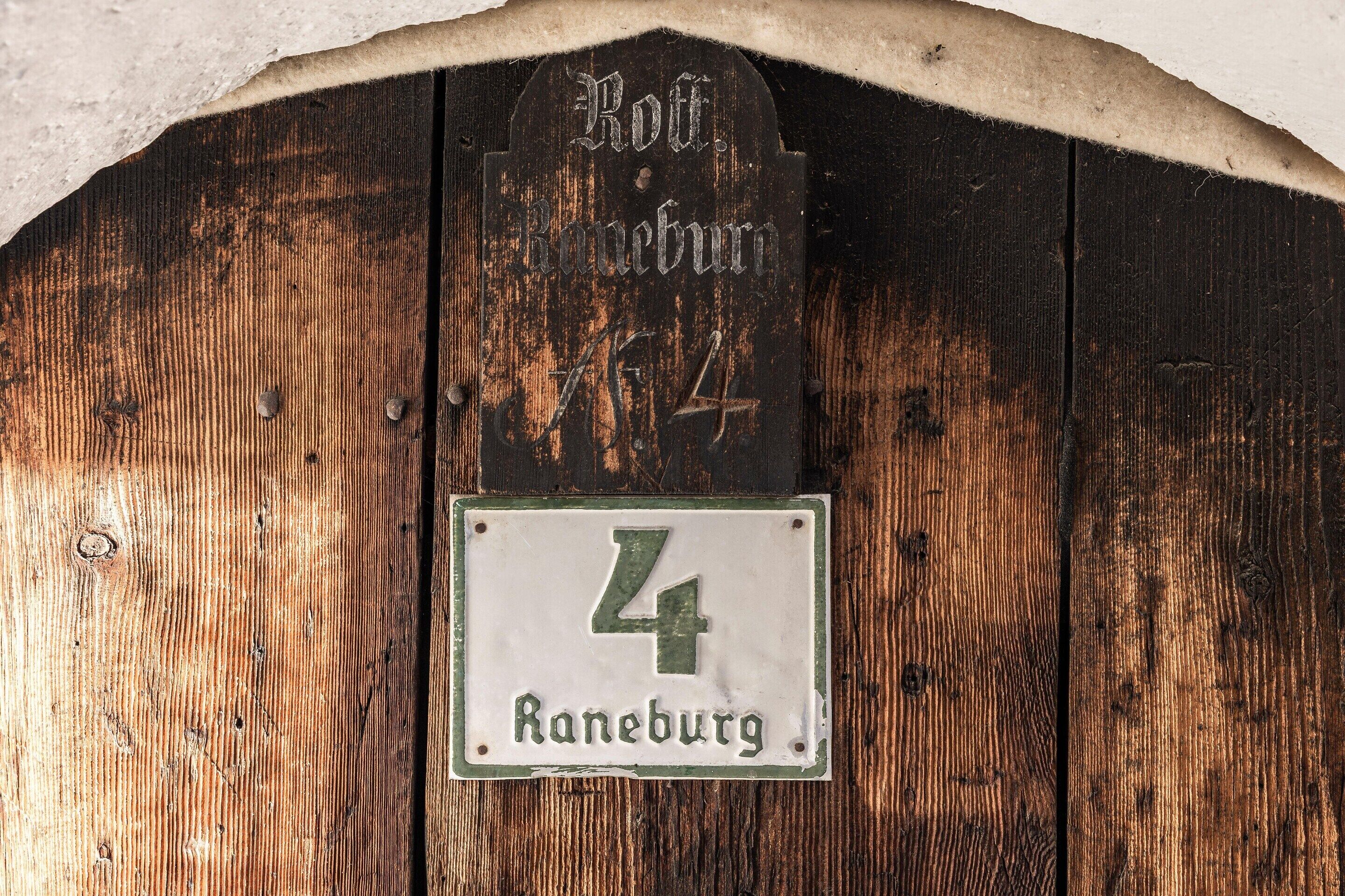Una puerta de madera rústica con un cartel arriba que dice 'Rothenbürg' y un letrero más pequeño abajo con el número '4'.