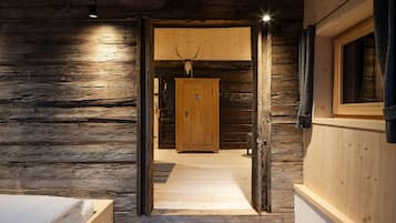 Een blokhut interieur met een houten deur die leidt naar een gang, een bed en een raam.