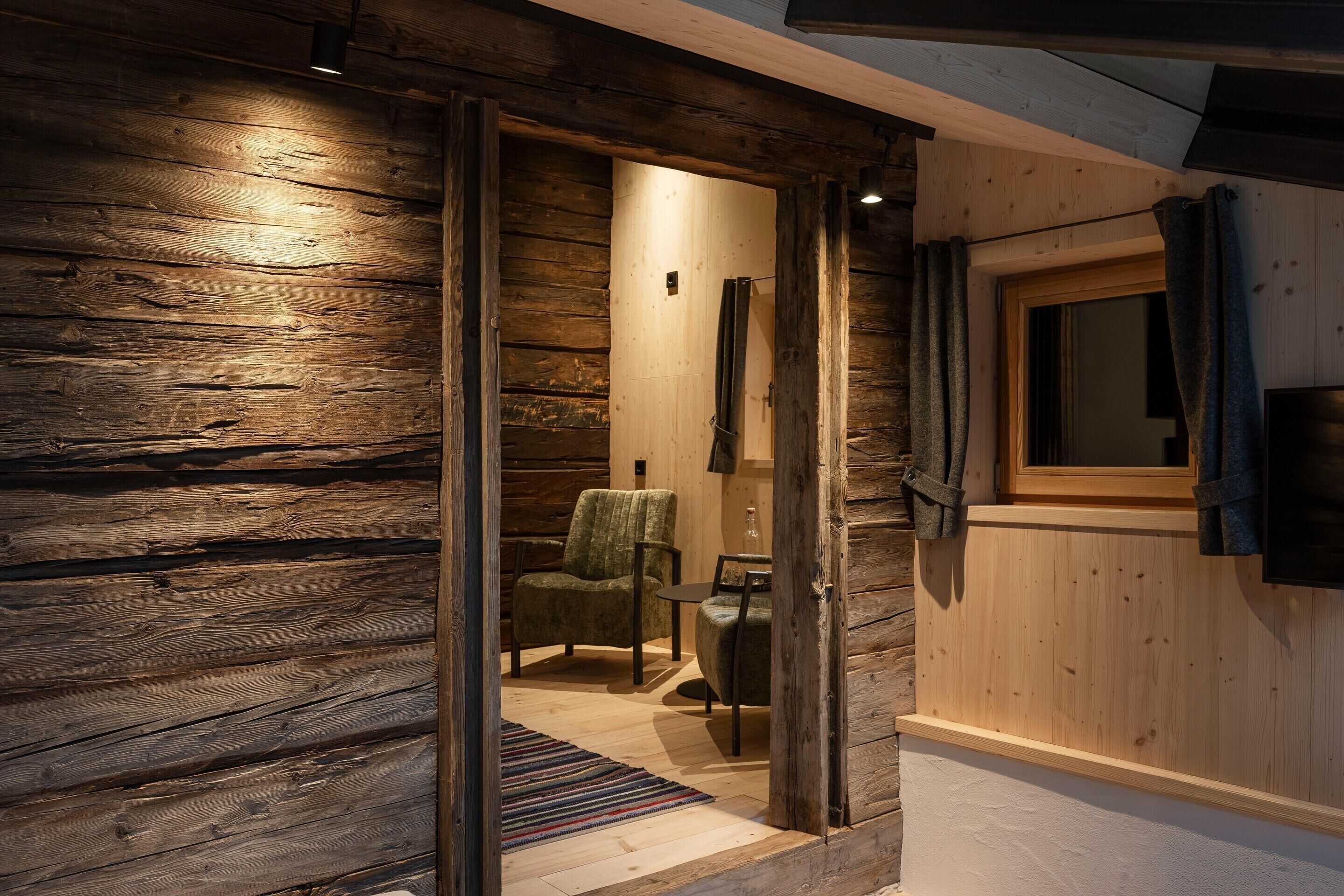 Un interior de madera con una puerta corredera que da a una habitación con una silla y una pequeña mesa.