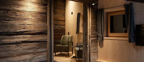 Un interior de madera con una puerta corredera que da a una habitación con una silla y una pequeña mesa.