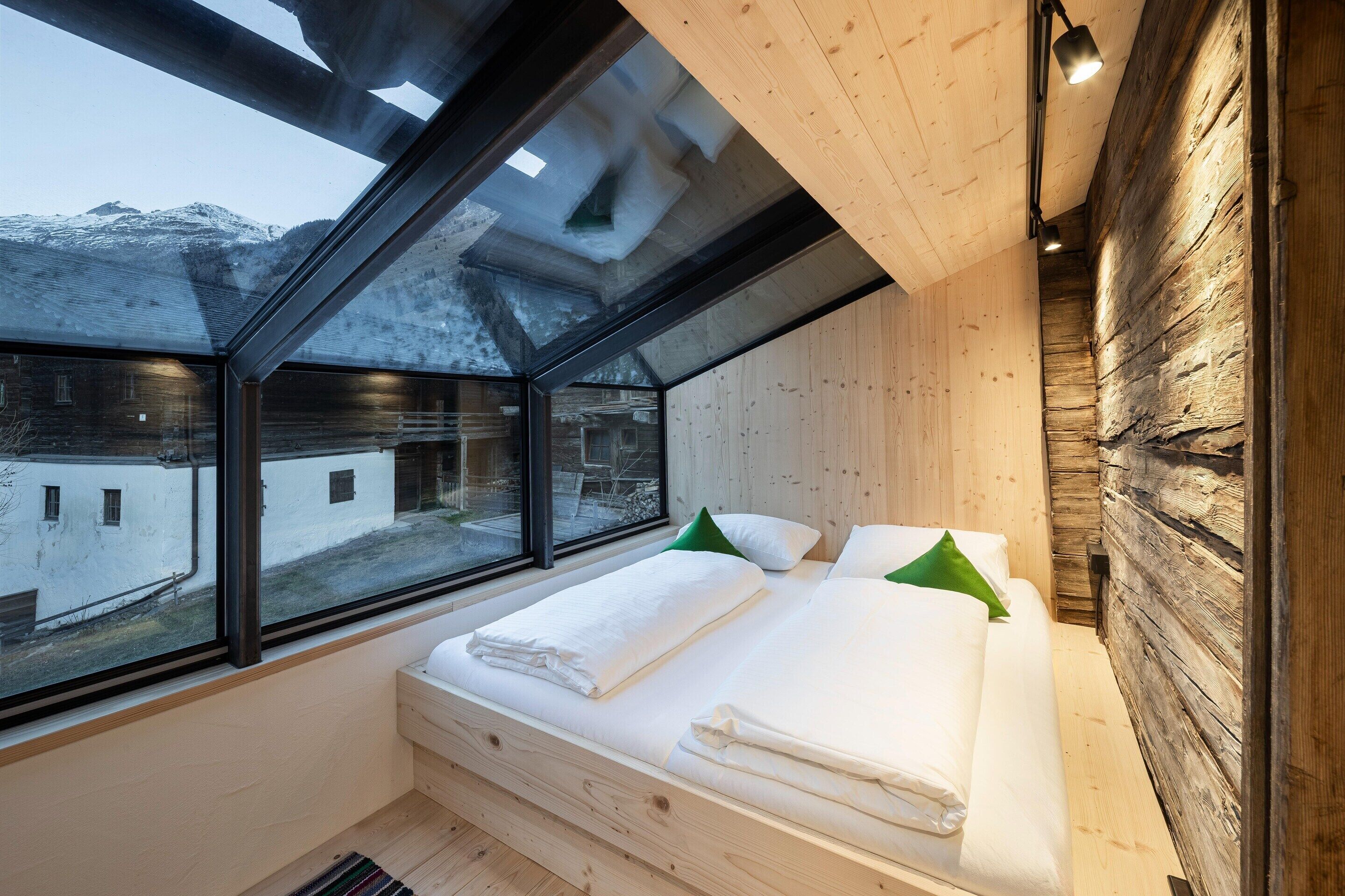 Une chambre avec une grande lucarne, des murs en bois et un lit avec des oreillers.