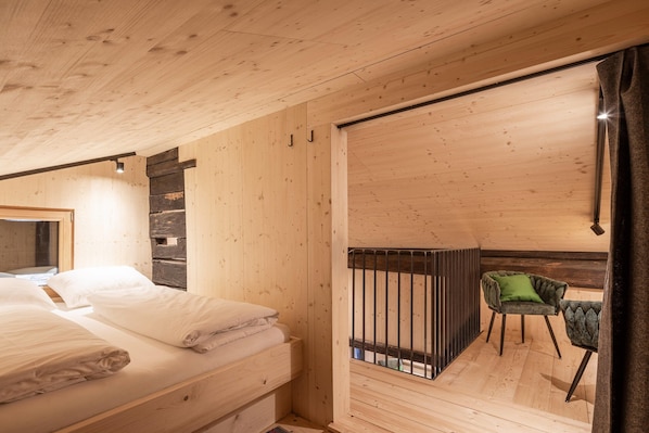 A wooden interior with a bed, a chair, and a sliding door leading to an outdoor area. - Historic Chalet Raneburg (Matrei in Osttirol)