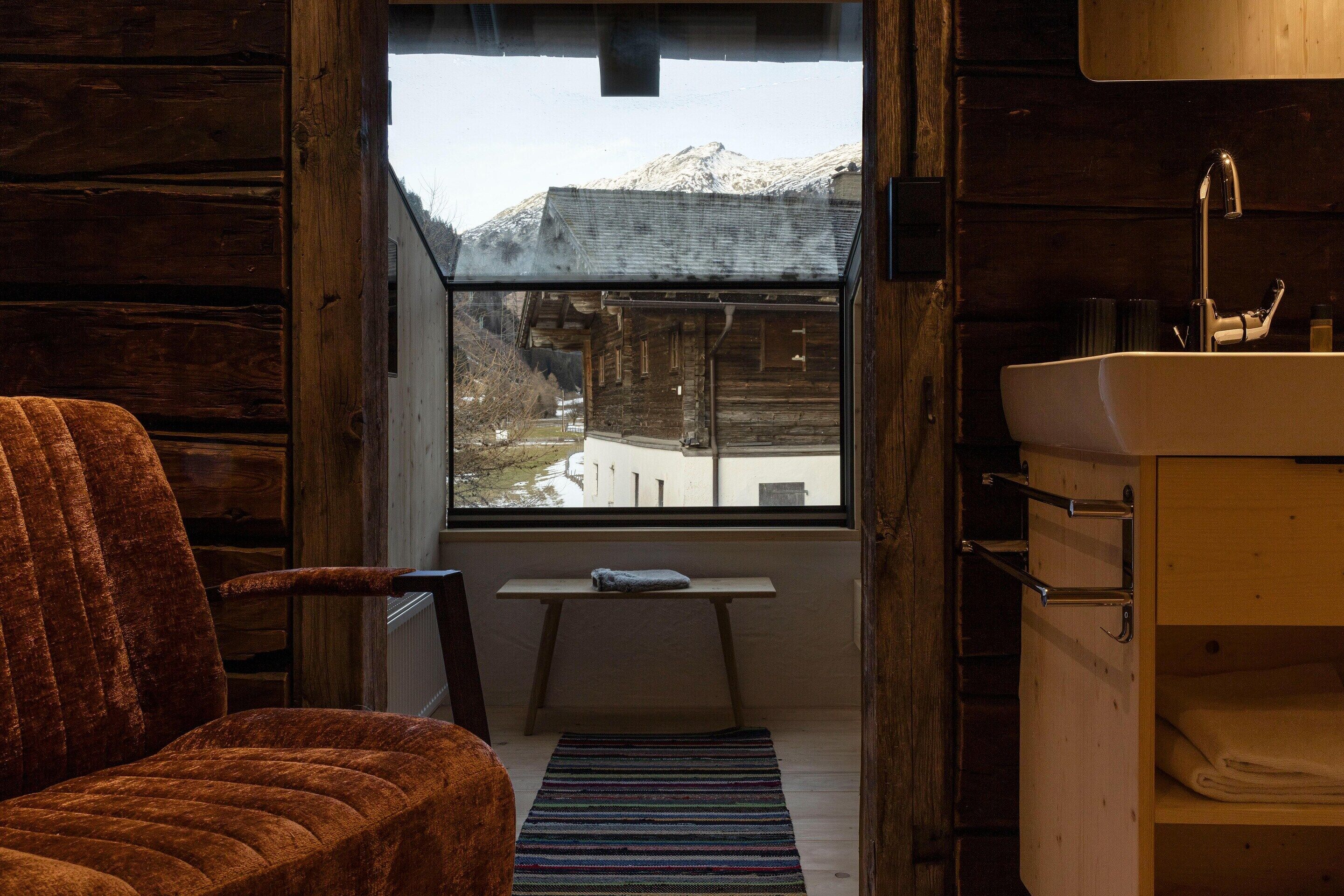 Interior rústico de madera con vista a una montaña nevada a través de una ventana.