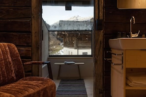A rustic wooden interior with a view of a snowy mountain through a window. - Historic Chalet Raneburg (Matrei in Osttirol)