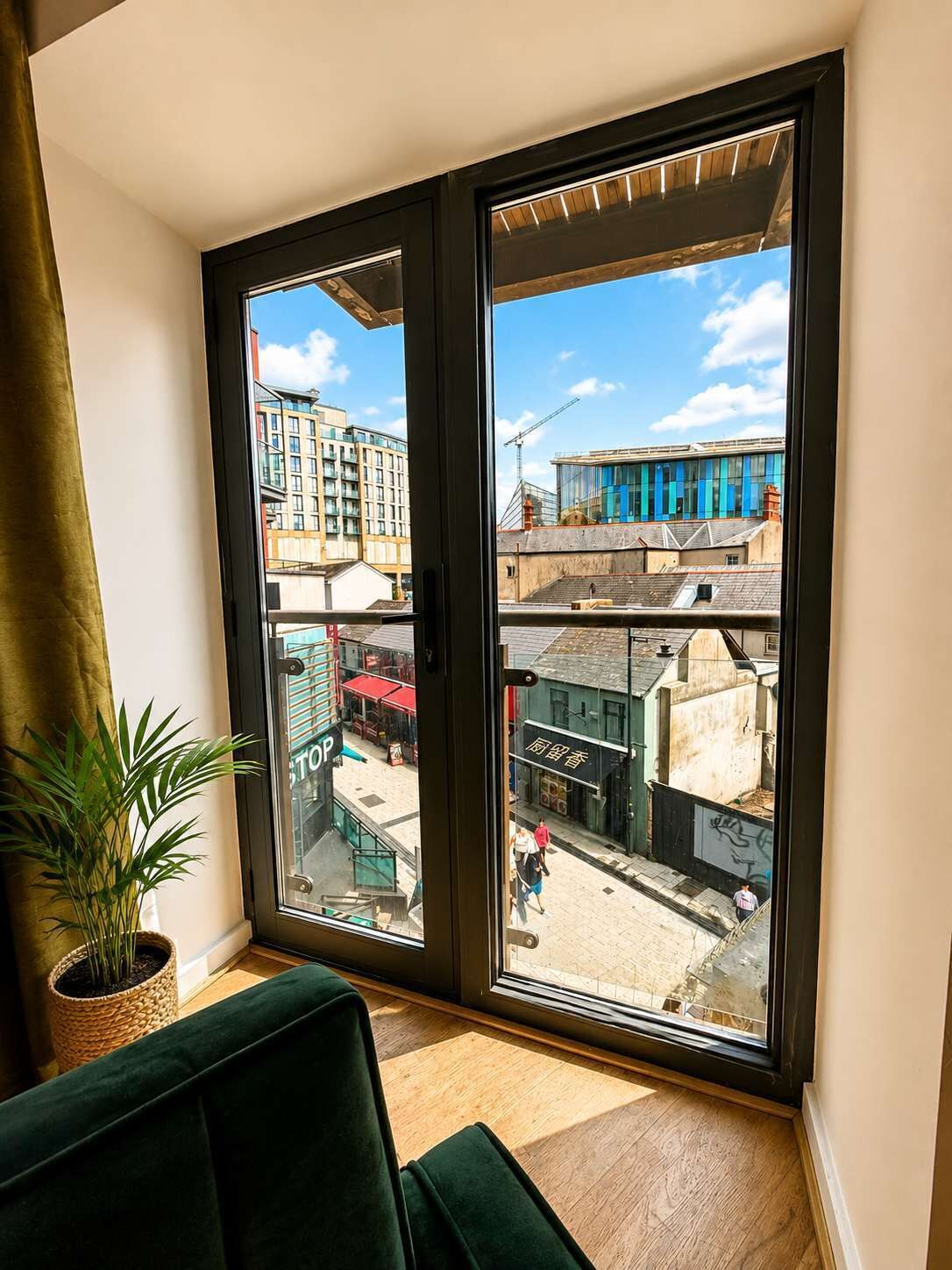 A room with a large sliding glass door leading to an outdoor area with buildings and a street.