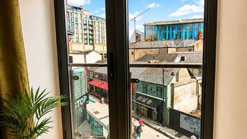 A room with a large sliding glass door leading to an outdoor area with buildings and a street.