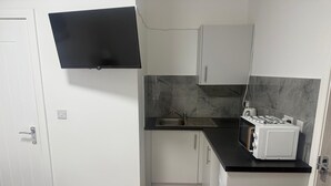 Ett kompakt kök med en inbyggd gasspis, en diskho och vita skåp.