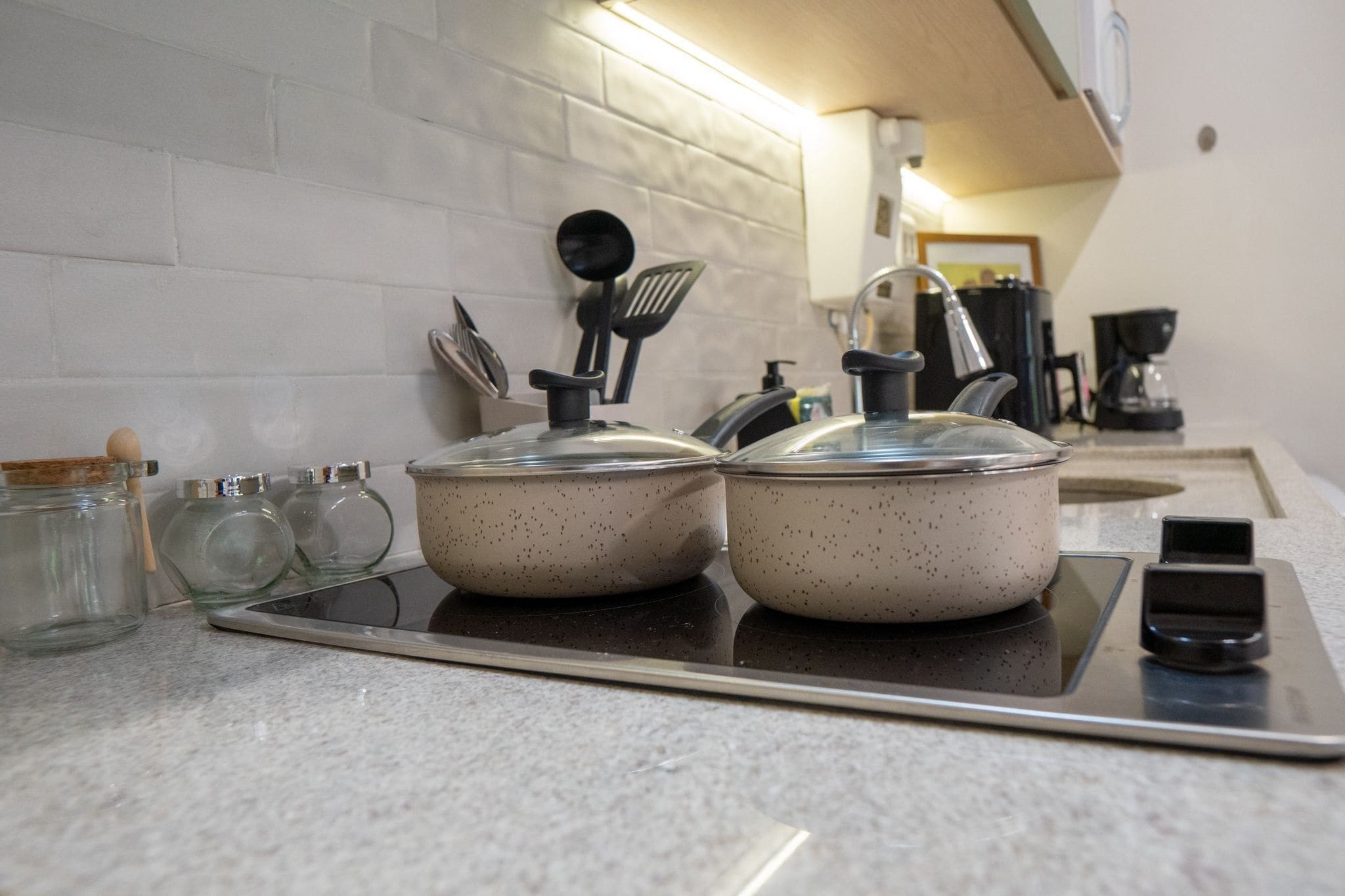 A kitchen with two pots on a stove, a coffee maker, and a scale on the counter.
