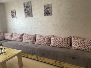 A living room with a sofa, patterned cushions, a coffee table, and wall art.