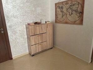 A room with a wooden cabinet, a world map on the wall, and a door.