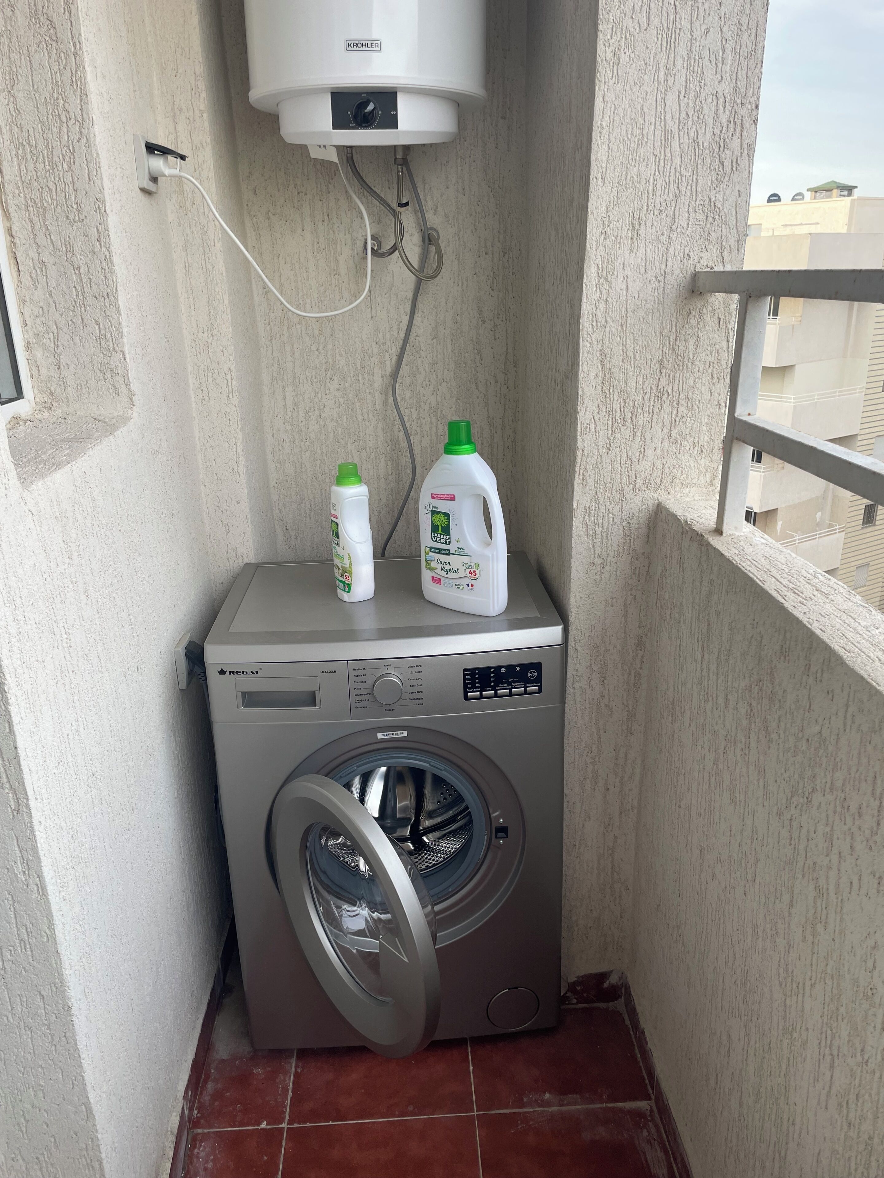A compact washing machine with a control panel, a water heater mounted above it, and two detergent bottles on top.