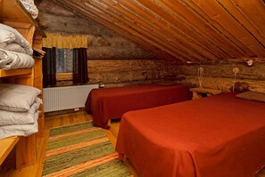 Ein gemütliches Schlafzimmer im Dachgeschoss mit zwei Betten, einem Heizkörper und einem Fenster mit Vorhängen.