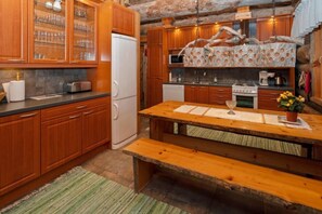 A kitchen with wooden cabinets, a refrigerator, a stove, and a dining table with benches. - Riekkoveska | Spacious 4BR Villa for Families (Ruka)