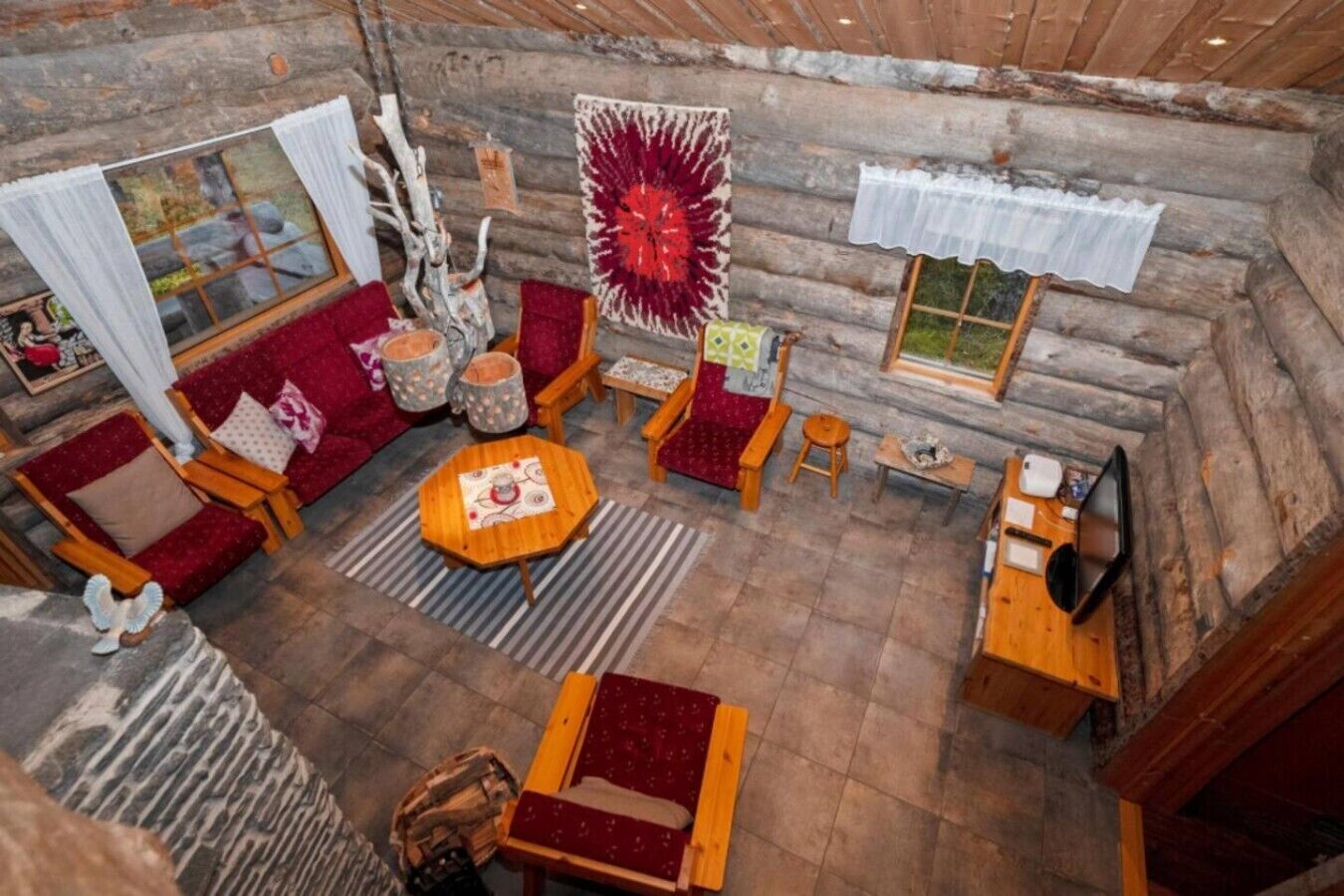 L’intérieur d’une cabane en rondins, avec un coin salon confortable, une petite table et une fenêtre avec des rideaux.