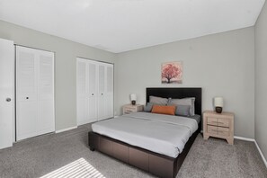 A bedroom with a bed, two nightstands, a headboard, a closet with louvered doors, and a wall-mounted picture. - Comfortable 2BR Retreat at Country Lakes (Indianapolis)