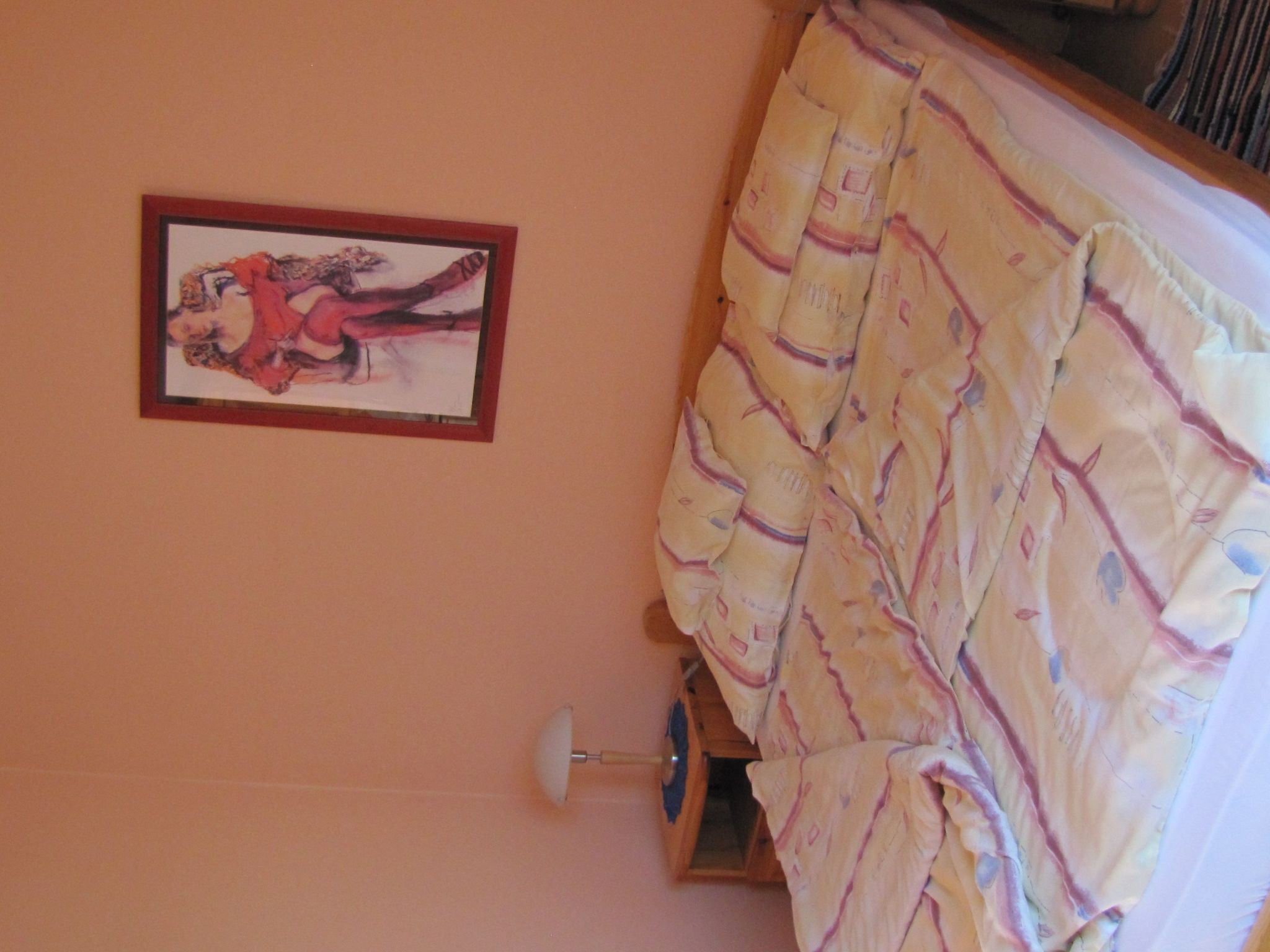A room with a bed covered in a striped blanket, a framed picture on the wall, and a door with a handle.