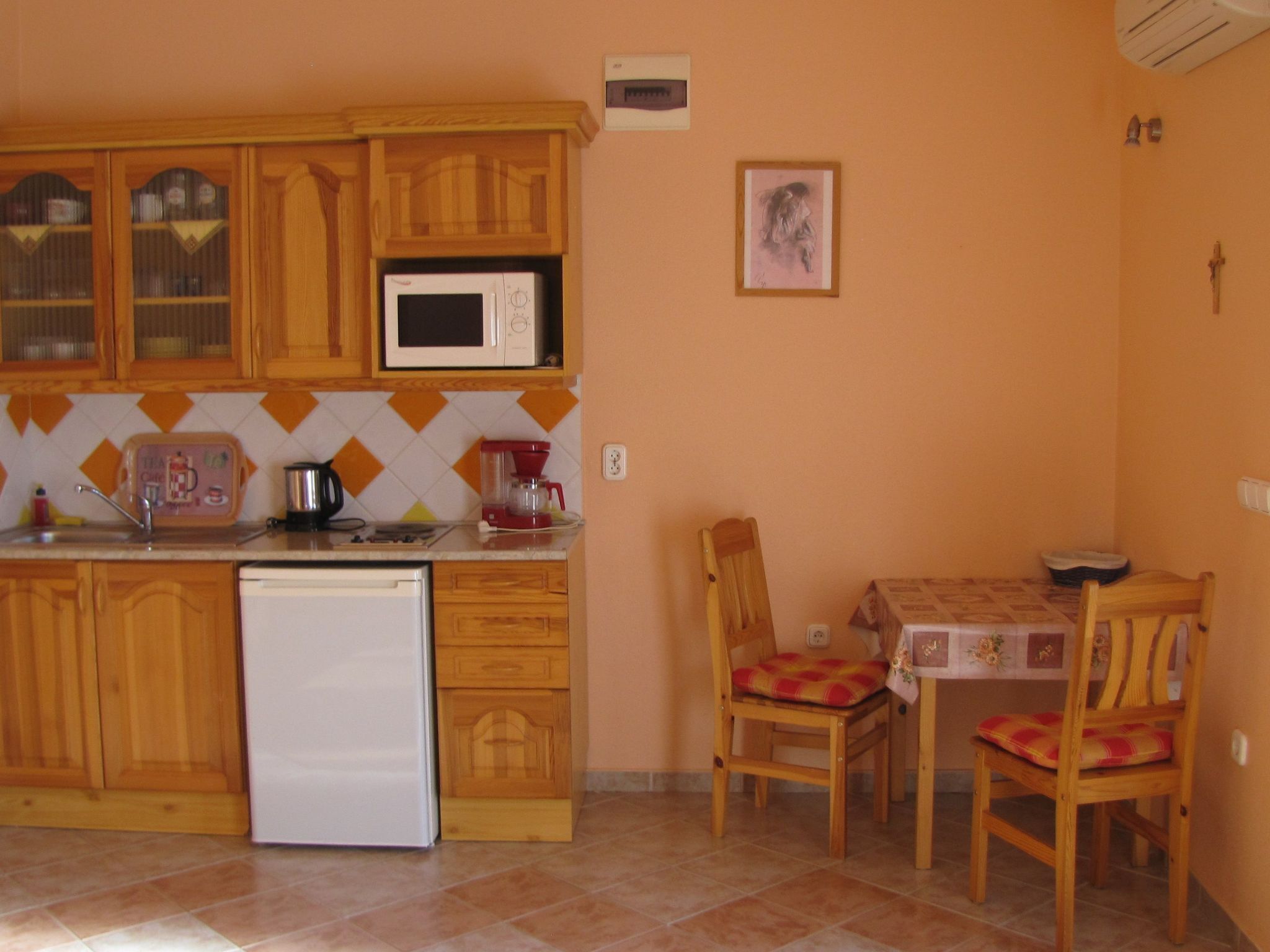 A compact kitchen with wooden cabinets, a microwave, a coffee maker, and a table with chairs.