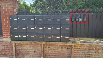 Una fila di cassette postali nere con etichette, fissate a un muro in mattoni.