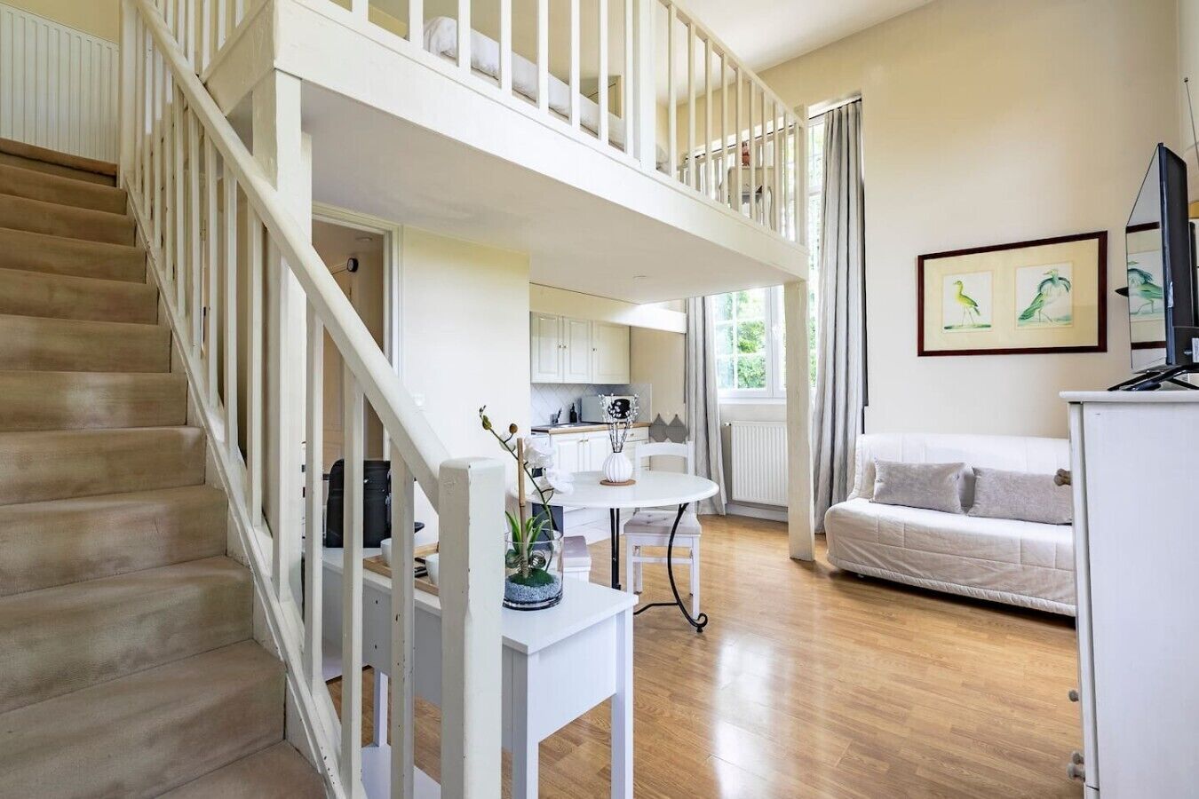 A spacious living area with a staircase, a dining table, and a sofa.