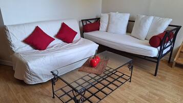 A living room with a white sofa, red cushions, a black coffee table, and a red apple on the table.