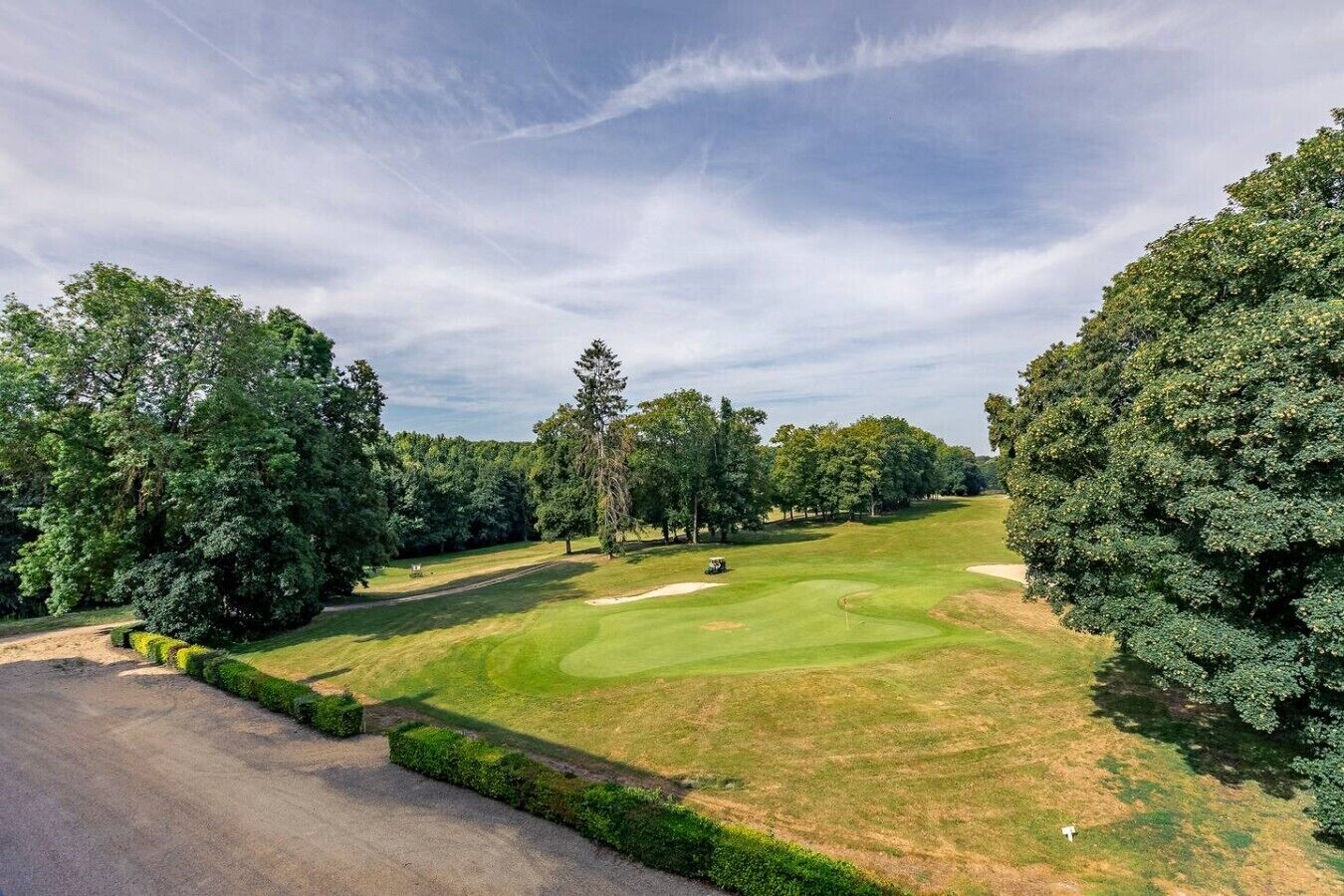 A golf course with a clear sky, surrounded by trees.