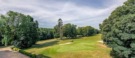 Un campo de golf con cielo despejado, rodeado de árboles.