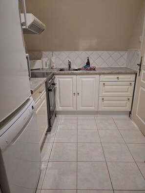 Uma cozinha com armários brancos, uma pia de aço inoxidável e um forno embutido.
