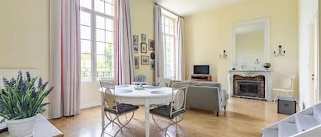 Amplia sala de estar con chimenea, comedor con mesa y sillas, y una zona de estar con sofá.