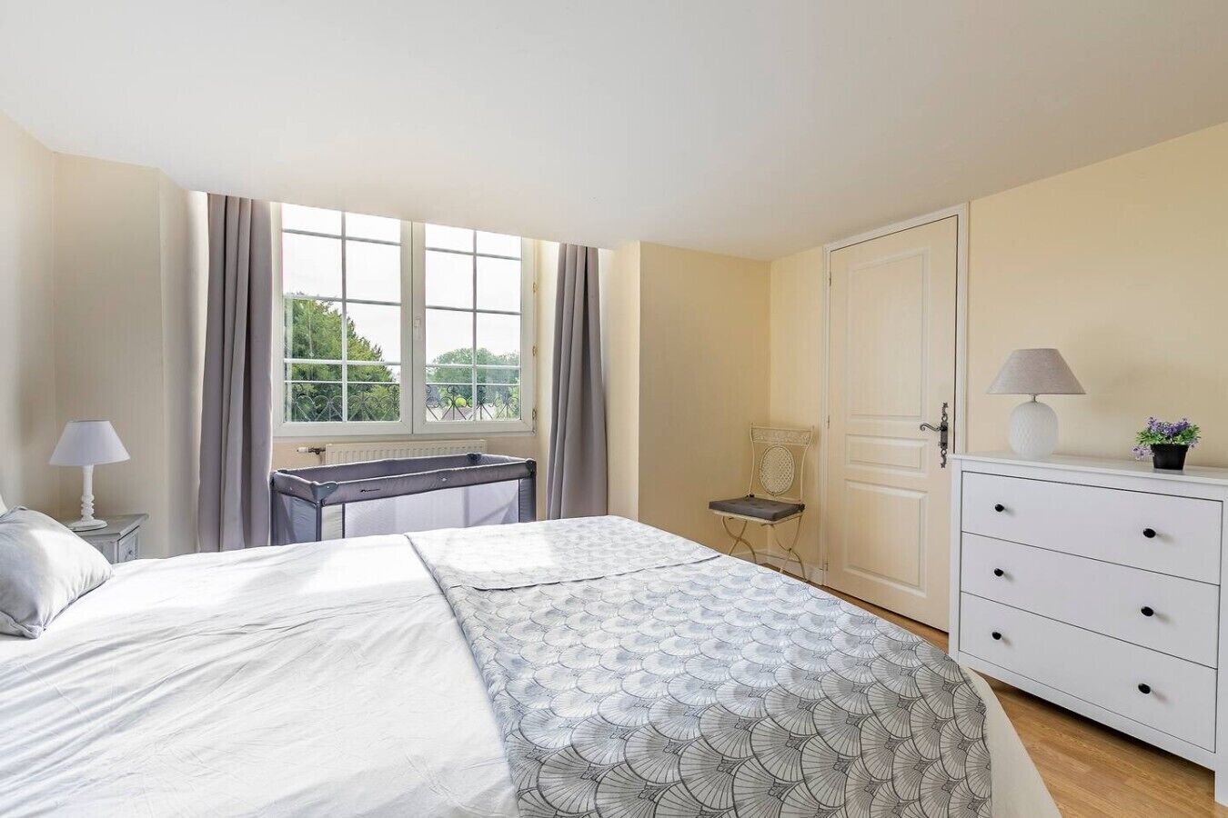 Un dormitorio con cama, escritorio, silla, cómoda y ventana con cortinas.
