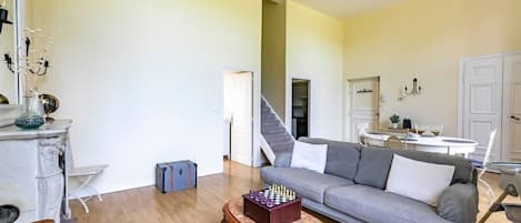 Una sala de estar con un sofá gris, una mesa de centro de madera y un tablero de ajedrez.