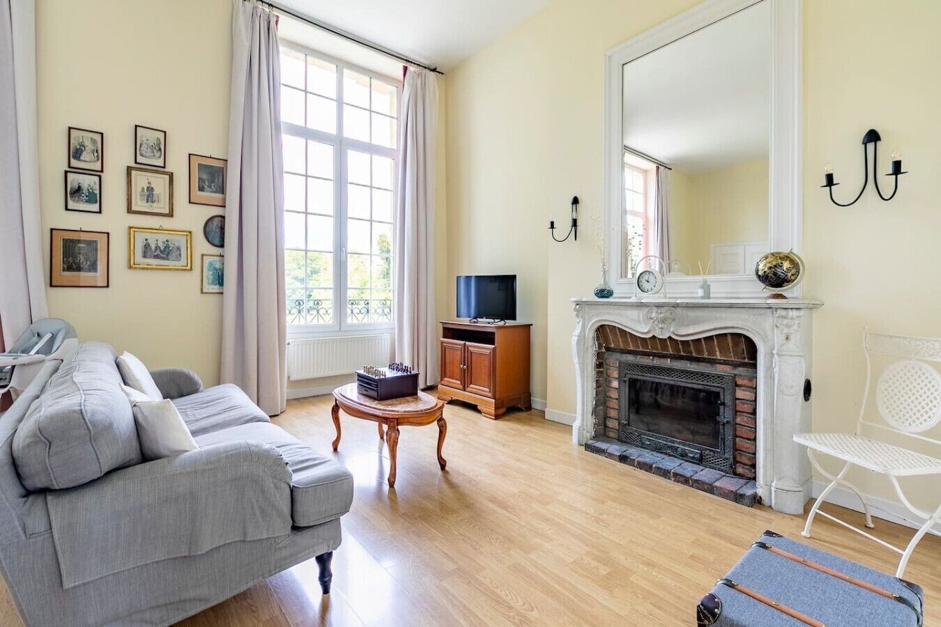 Een woonkamer met een open haard, een bank, een televisie en een eettafel.