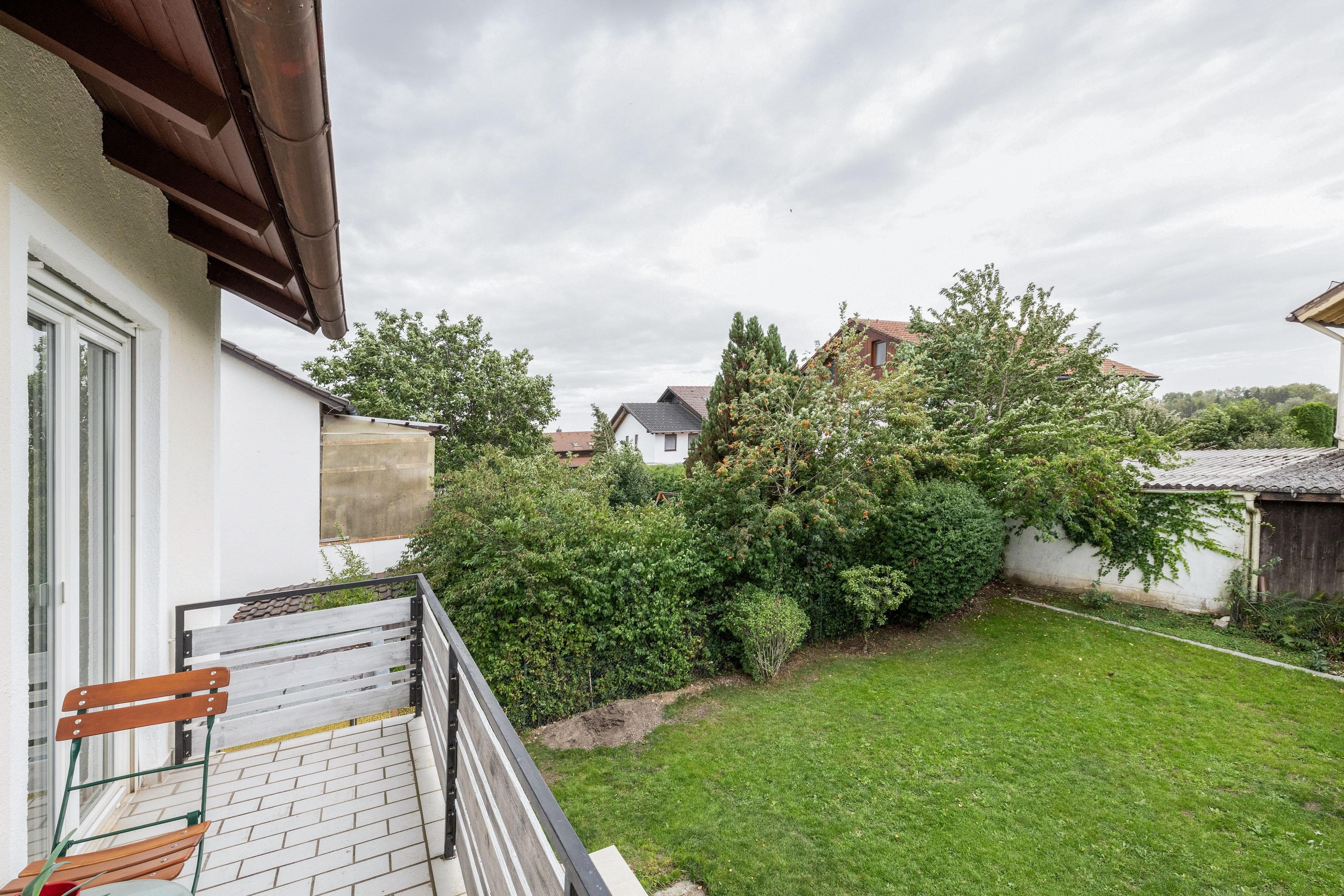 A residential property with a well-maintained lawn, a wooden bench, and a variety of trees and shrubs.