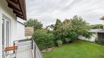 A residential property with a well-maintained lawn, a wooden bench, and a variety of trees and shrubs.