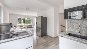 Une cuisine moderne dotée d’un four encastré, d’un réfrigérateur en acier inoxydable et d’un plan de travail en granit.
