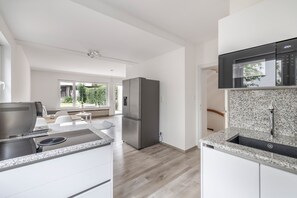 A modern kitchen with a built-in oven, a stainless steel refrigerator, and a granite countertop.