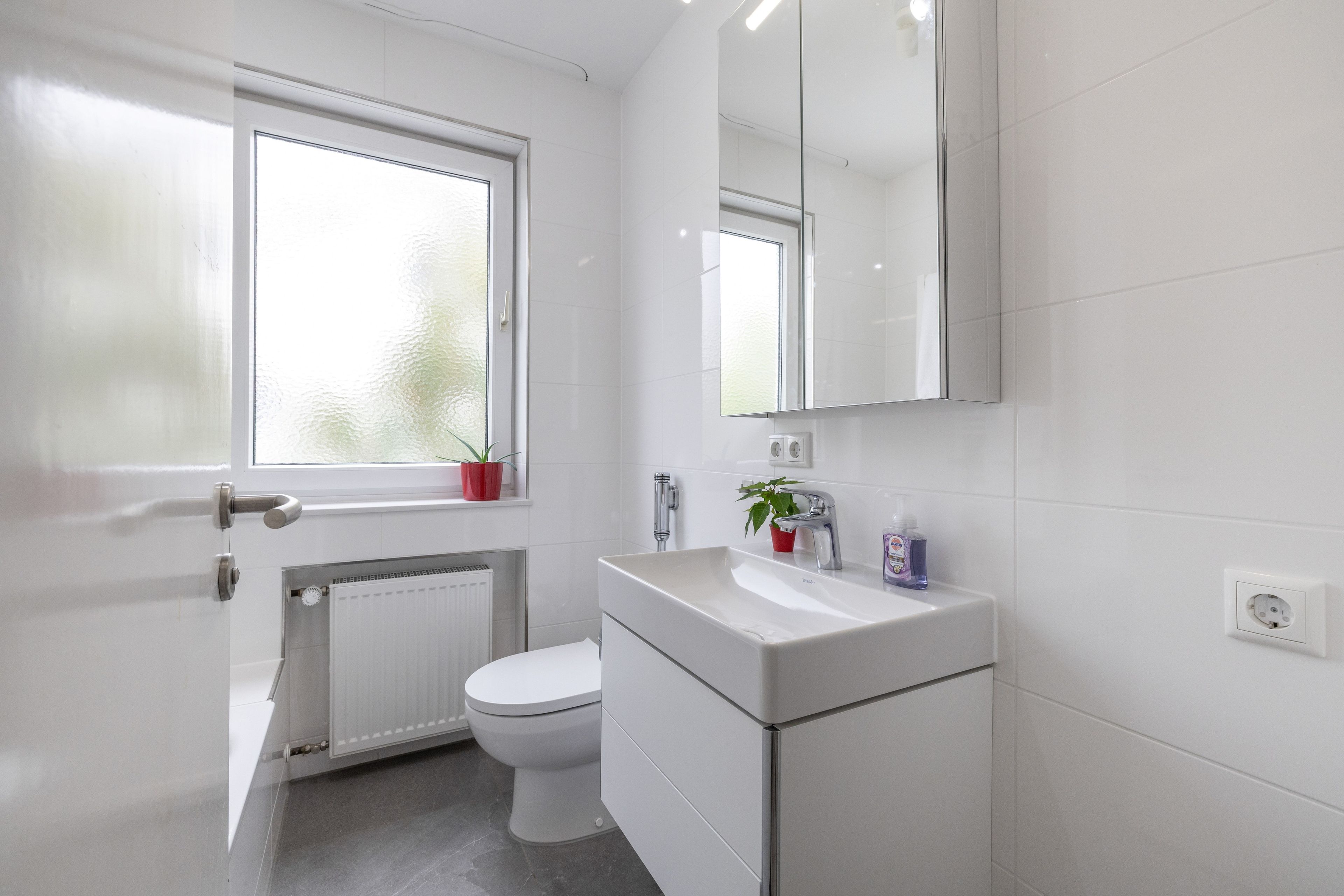 Ein modernes Badezimmer mit Toilette, Waschbecken und Spiegel.