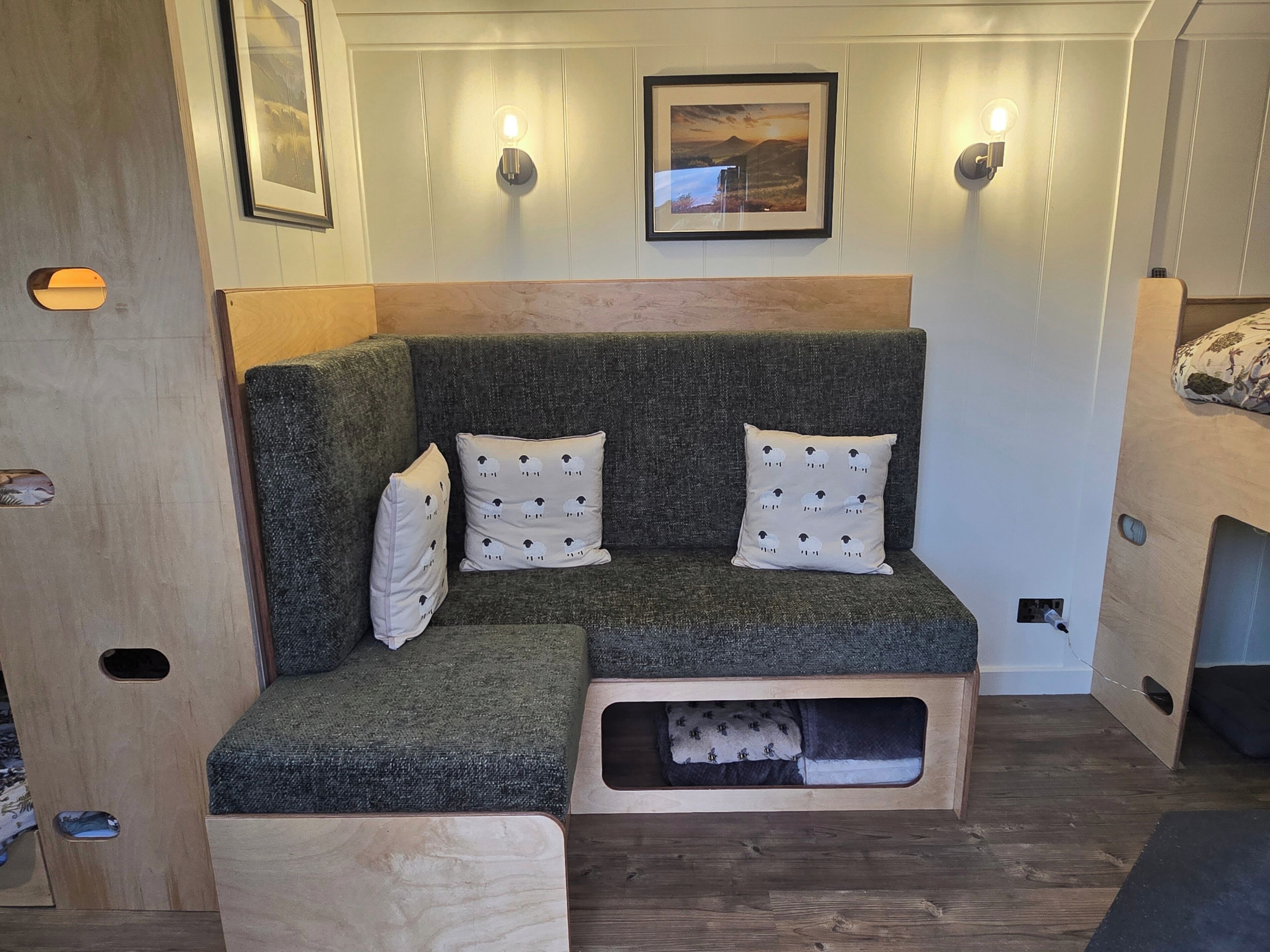 A cozy seating area with a cushioned bench, a small built-in storage compartment, and wall-mounted lighting.