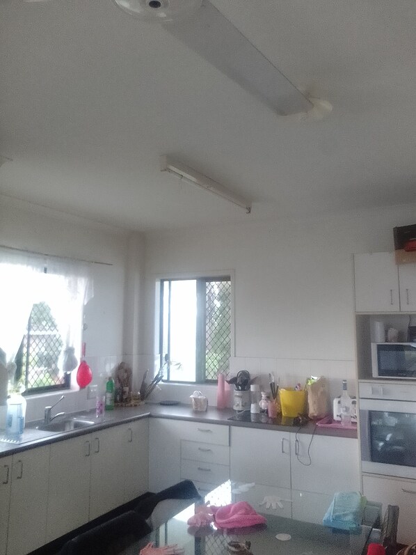 A kitchen with white cabinets, a microwave, and various kitchen items on the counter.