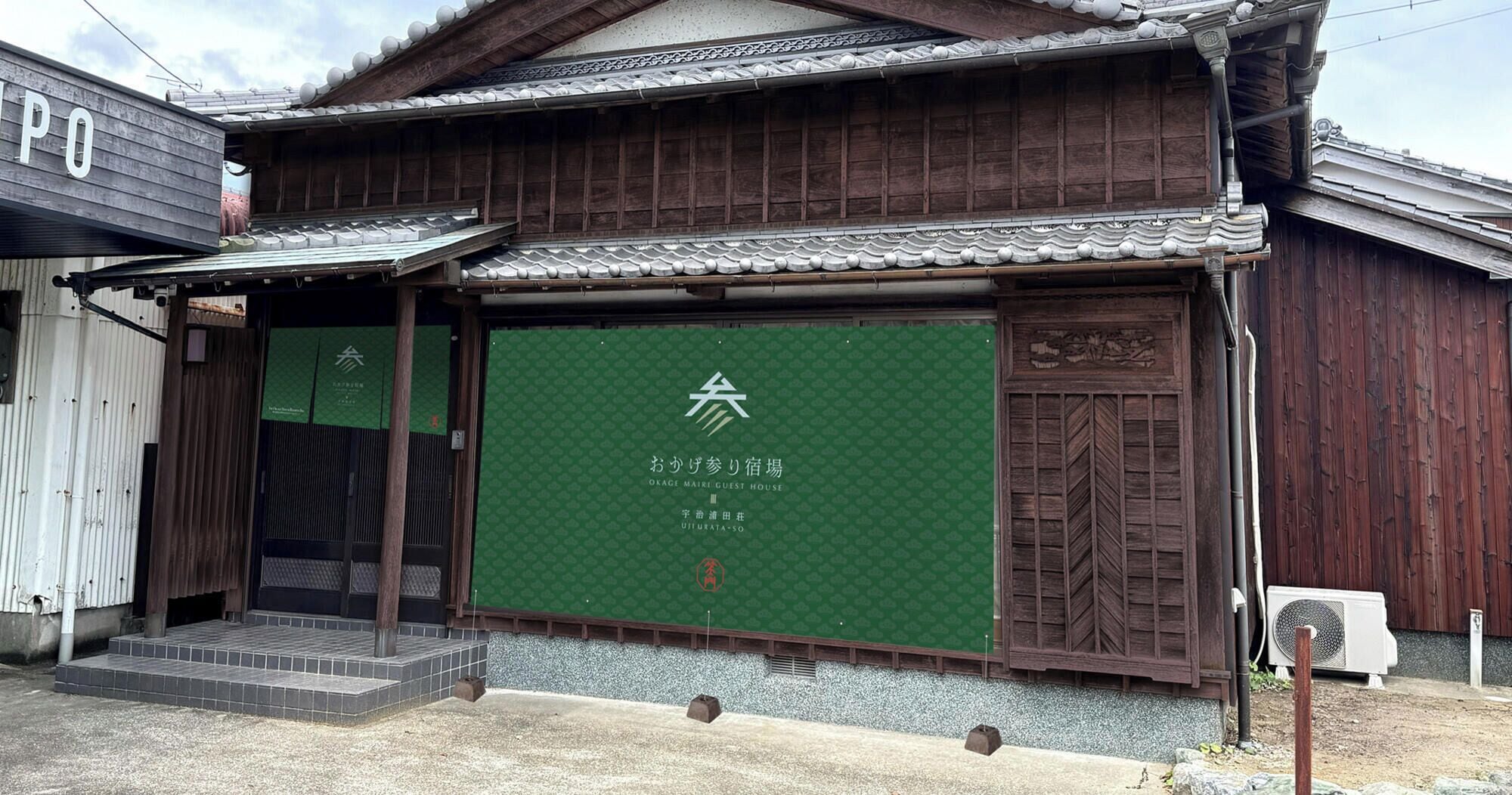 Un edificio japonés tradicional con puerta corredera verde, entrada de madera y un pequeño porche.