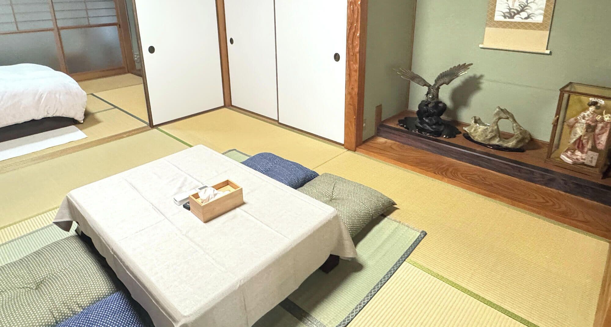 Una habitación japonesa tradicional con suelo de tatami, una cama baja y una mesita con una caja encima.